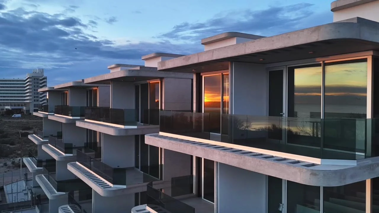 Edificios modernos con balcones y vista al mar sobre la costanera de Puerto Madryn al atardecer